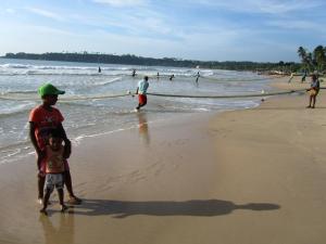 zwei Kinder stehen am Strand mit einem Boot in der Unterkunft Isana Beach House in Tangalle