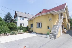 a yellow house with a staircase in front of it at Hi-Bp Garden city Batsanyi Apartment 3 Rooms, Apartment upstairs near the city train with FREE PARKING in Budapest
