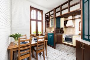 a kitchen with green cabinets and a wooden table and chairs at Apartament Chrobrego z Balkonem Przy Plaży - Praia Apartments in Sopot