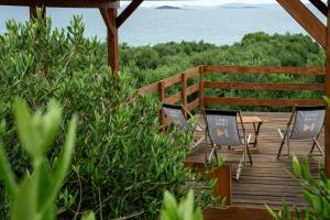 a wooden deck with chairs and a table and the ocean at SUNSET CAMPING in Pakoštane