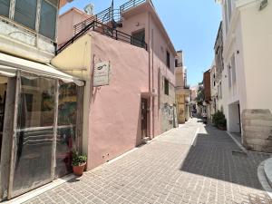 une rue dans une vieille ville avec un bâtiment rose dans l'établissement TROCHALOS, à Réthymnon