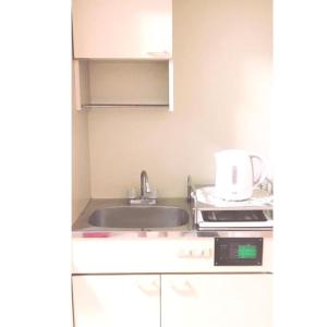 uma pequena cozinha com um lavatório e um micro-ondas em Guest house Shijo K12 A202 em Quioto