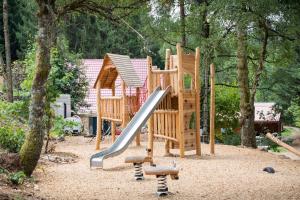 a wooden playground with a slide in a park at Huttopia Forêt des Vosges in Barbey-Séroux