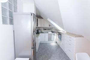 a white kitchen with white cabinets and a refrigerator at Hi-Bp Garden city Batsanyi Apartment 3 Rooms, Apartment upstairs near the city train with FREE PARKING in Budapest