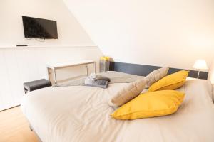 une chambre avec un grand lit avec des oreillers jaunes dans l'établissement Grand duplex bord de plage avec Terrasse par Groom, à Guidel