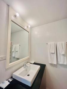 bagno bianco con lavandino e specchio di PJ Guest House a Chiang Rai