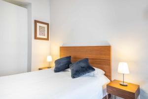 a bedroom with a white bed with two blue pillows at Chueca Gran Via Recoletos Libertad 24 8 in Madrid