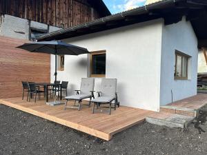 eine Terrasse mit Stühlen, Tischen und einem Sonnenschirm in der Unterkunft Apart Bader in Ehrwald