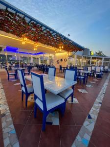 a patio with a white table and blue chairs at منتجع شاطئ النخيل in Half Moon Bay