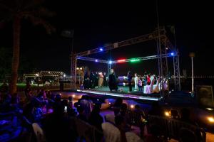 a group of people watching a show on a stage at night at منتجع شاطئ النخيل in Half Moon Bay +155 photos