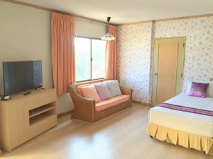 um quarto com uma cama, uma televisão e uma cadeira em Takiab Beach Resort em Hua Hin