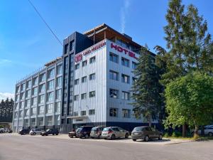 a hotel building with cars parked in a parking lot at HOTEL DOUBLE RED CARS Museum in Brezno