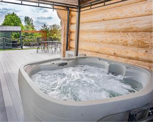 eine Whirlpool-Badewanne auf einer Terrasse mit einem Tisch in der Unterkunft Palmowe Wzgórze Skoszewo - Domek Dolny in Skoszewo