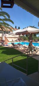 a woman sitting in a chair under an umbrella next to a pool at Helena Inn in Svoronata