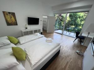 ein Schlafzimmer mit einem großen weißen Bett und einem Balkon in der Unterkunft MySchönbrunn Apartments in Wien