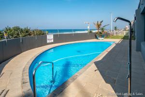 a swimming pool with the ocean in the background at Isikulu 27B in Umdloti