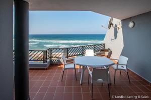 a balcony with a table and chairs and the ocean at Isikulu 27B in Umdloti