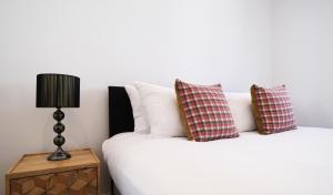 ein Bett mit zwei Kissen und einer Lampe auf einem Tisch in der Unterkunft Ealing Common Apartment with Balcony in London