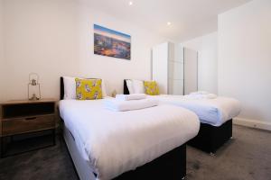 2 Betten in einem Zimmer mit weißen und gelben Kissen in der Unterkunft Ealing Common Apartment with Balcony in London
