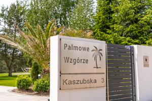 a sign for a villa with a palm tree at Palmowe Wzgórze Skoszewo - Domek Dolny in Skoszewo