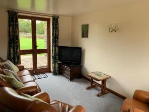 a living room with a couch and a television at Irelands Farm Cottages in Birmingham