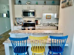 uma cozinha com cadeiras azuis e amarelas num balcão em 215 C2 GP-The Treehouse em Coffeyville