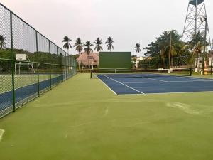 a tennis court with a tennis net and palm trees at Casa Villas del Pacifico Puerto San José in Puerto San José