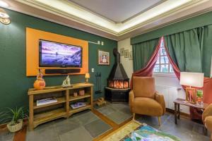 uma sala de estar com uma televisão e uma cadeira em Tri Hotel Le Chateau em Gramado