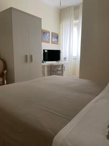 a white bedroom with a bed and a desk at Locanda Kon Tiki in Alassio