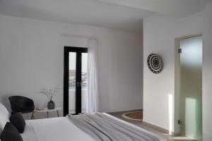 um quarto com uma cama, uma cadeira e uma janela em The Thermia Suites em Kythnos