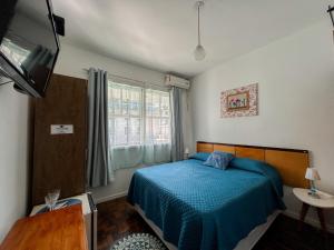 a bedroom with a blue bed and a tv at A Primeira Vista in Florianópolis
