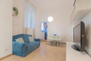 een woonkamer met een blauwe bank en een tv bij La Corte by HelloElba in Portoferraio