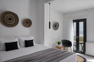 a white bedroom with a bed and a balcony at The Thermia Suites in Kithnos