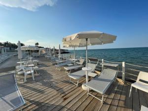 eine Gruppe von Stühlen und Sonnenschirmen auf einer Holzterrasse in der Unterkunft Fabris Palace in Trani