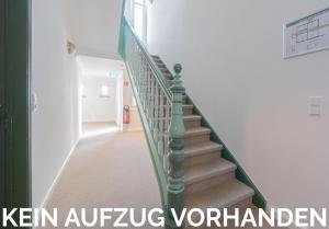 a staircase in a building with a green railing at Logierhaus am Denkmal in Norderney