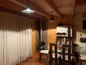 a kitchen and dining room with a table and chairs at Cabaña Coñaripe in Coñaripe