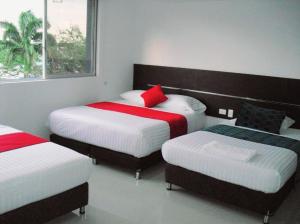 a bedroom with three beds with red and white sheets at AW Hotel Sport in Cali