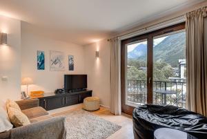 a living room with a couch and a large window at APARTMENT COSMIQUES - Alpes Travel - Central Chamonix - Sleeps 4 in Chamonix