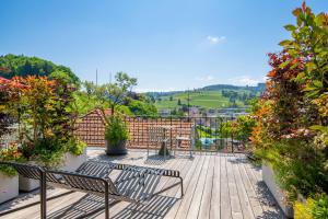 um deque com dois bancos e flores numa varanda em Linde Heiden Swiss Quality Hotel em Heiden