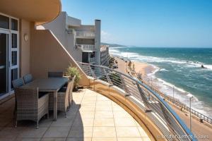 a balcony with a table and chairs and a beach at Sugar Beach 2B in Umdloti