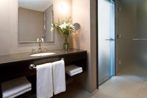 a bathroom with a sink and a vase of flowers at NH Buenos Aires Tango in Buenos Aires