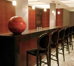 une rangée de chaises dans un bar avec un vase rouge dans l'établissement NH Buenos Aires Tango, à Buenos Aires