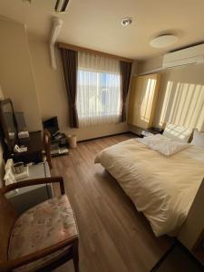 ein Hotelzimmer mit einem großen Bett und einem Stuhl in der Unterkunft Hotel Shibukawa Hills in Shibukawa