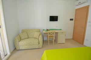 a bedroom with a chair and a desk with a television at B&B Lu Cantoru in Marina di Pescoluse