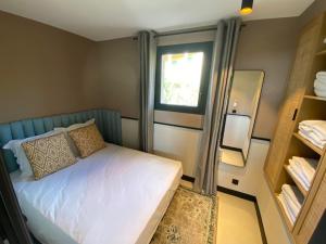 a small bedroom with a bed and a window at Le Mazet des maisons du golf in Sainte-Maxime