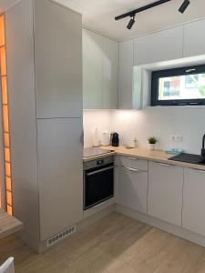 a kitchen with white cabinets and a window at Római Ház Apartman in Siófok