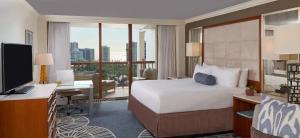 a hotel room with a bed and a desk and a television at Naples Grande Beach Resort in Naples