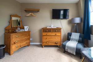 a bedroom with a dresser and a mirror and a chair at Sleepy Puffin Guest House in Tenby