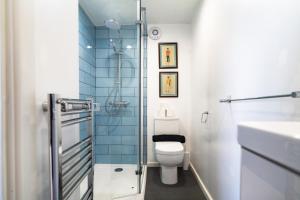 a bathroom with a toilet and a glass shower at Sleepy Puffin Guest House in Tenby
