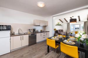 a kitchen and dining room with a table and yellow chairs at Apartman Bijeca - Medulin in Medulin